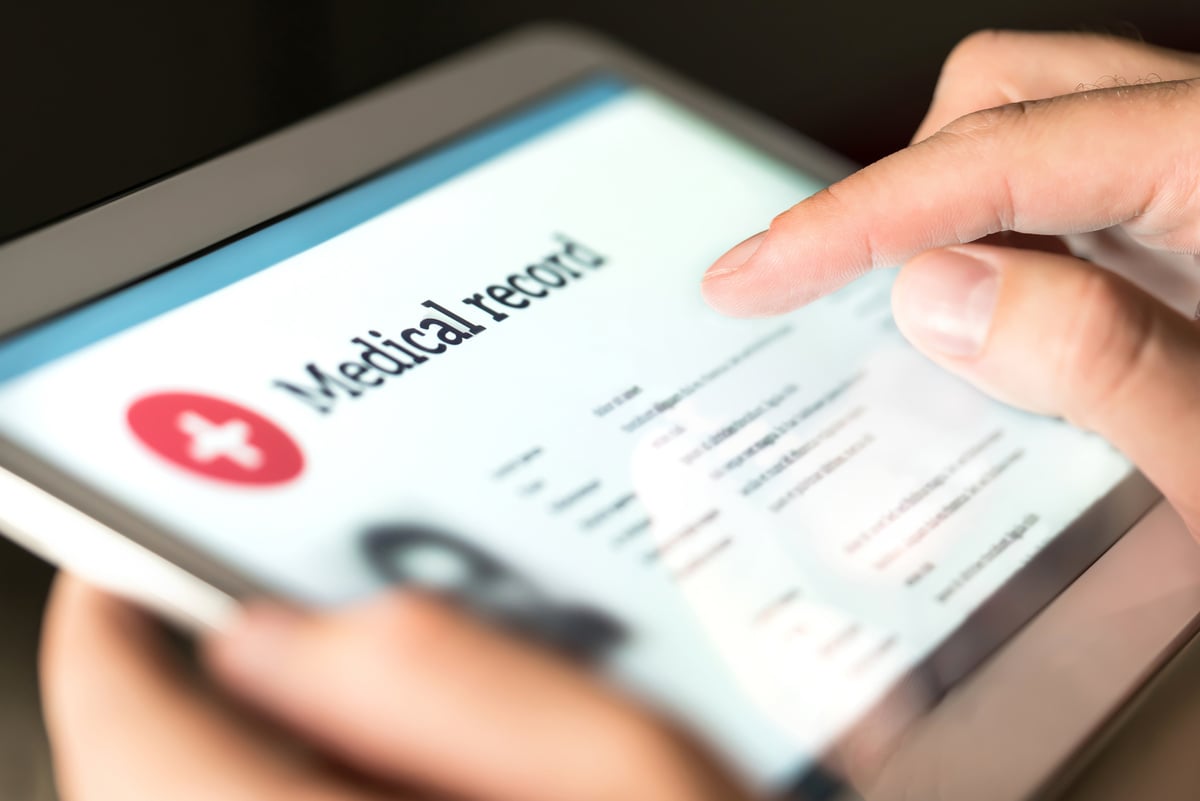 Electronic medical record with patient data and health care information in tablet. Doctor using digital smart device to read report online.